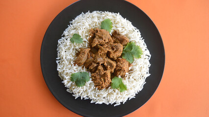 A top view og lamb korma with basmati rice and coriander leaves.