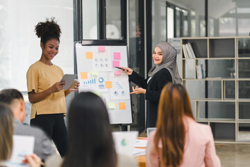 Wall Mural - Diverse business team analyzing data and discussing strategies during an office meeting, using documents and a laptop.