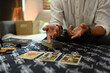 © Prathankarnpap - Fortune teller spreading Tarot cards laid out on a table covered with a mystical cloth. Forecasting and divination concept