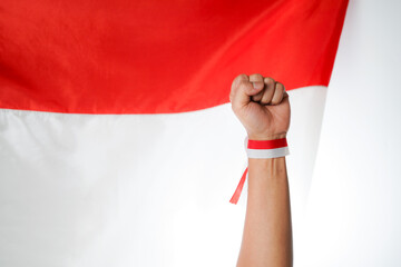 Human hand clenched into a fist with red and white ribbon with Indonesian flag background