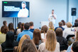 © Anton Gvozdikov - Group of people in an auditorium listening to a person giving a presentation at a business conference. Professional setting focused on learning and networking.