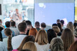 © Anton Gvozdikov - Large group of people attending a business conference, focusing on a speaker presenting on stage. Professional event with business attire and engaged audience.