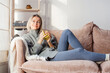 © Tatyana Gladskih - Happy dreamy middle aged woman sitting on sofa in living room with cup of tea or coffee
