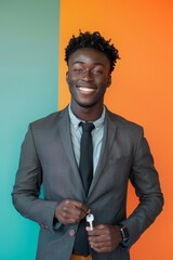 Wall Mural - A young man in a suit holding keys, standing against a colorful background