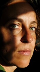 Wall Mural - A woman with green eyes looks away from the camera, with sunlight illuminating her face