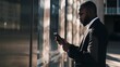 © Felippe Lopes - Focused businessman checking his phone while standing outside a modern office building