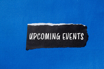 Upcoming events message written on ripped torn black paper piece with blue background. Conceptual upcoming events symbol. Copy space.