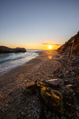 Hidden bay in sunrise. Looked at the small sand, pebble, beach in warm colors and the morning light. View of the sea at Xigia Sulfur Beaches, Ionian Islands, Greece