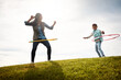 © peopleimages.com - Hoop, field and dance with nanny and girl, toys and fun in nature for holiday activity. Childcare, bonding and grass with female person in autumn, babysitter or cloudy sky in countryside for vacation