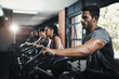 © peopleimages.com - People, exercise and cycling in gym for fitness or leg strength, cardio and muscle endurance for agility training. Recreation center, workout bike and machine for cardiovascular, wellness and power.