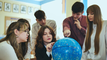 Students look at a globe of the starry sky in a classroom at school.