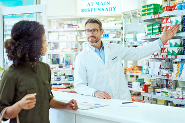 Poster - Man, pharmacist and shelf with customer for medication, option or choice at pharmacy. Mature medical employee talking to shopper and showing inventory, stock or pharmaceutical drugs at dispensary