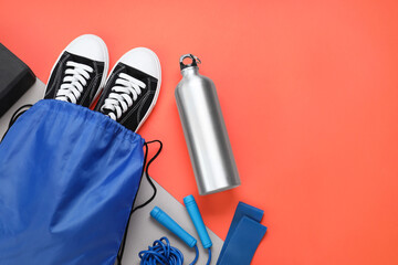 Wall Mural - Blue drawstring bag, thermo bottle, skipping rope and sneakers on red background, flat lay. Space for text