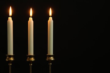 Wall Mural - Many burning candles on black background. Space for text