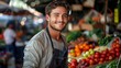 © Pinklife - Man in a market setting, surrounded by fresh produce and vibrant colors, wearing an apron and smiling, reflecting the atmosphere of a bustling and lively environment.