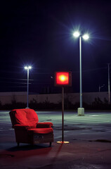 An empty parking lot at night, illuminated by two streetlights, with an old armchair and television set.Minimal creative urban concept.  