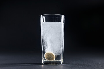 Wall Mural - Effervescent pill dissolving in glass of water on grey table