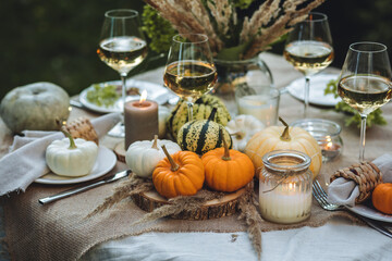 Wall Mural - Cozy fall table decoration for Thanksgiving family dinner, romantic autumn wedding outdoors with small pumpkins, candles. White wine. Countryside style, cottage core, beautiful elegant setting