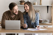 © fizkes - Smiling couple do paperwork in home kitchen, calculate expenses, check savings, pay utility bills through ebank application, plan family budget use laptop and calculator, feels satisfied, enough money