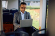 © Drazen - Happy businessman working on laptop in public transport.