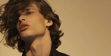 Close-up portrait of a young man with wavy hair, soft lighting, and a contemplative expression