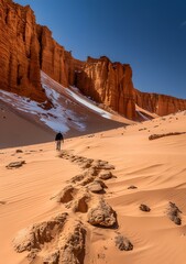 Canvas Print - Man walking alone in the desert with huge sand dunes in the background