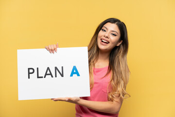 Wall Mural - Young Russian girl isolated on yellow background holding a placard with the message PLAN A with happy expression