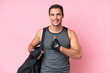 © luismolinero - Young sport caucasian man with sport bag isolated on pink background giving a thumbs up gesture