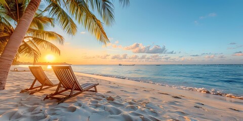 Two empty wooden beach chairs sit on a sandy beach with palm trees and the ocean in the background