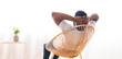 © Prostock-studio - African American man in a white shirt sits in a wicker chair and leans back, looking out a large window. He is relaxed and at ease, enjoying the view and the natural light streaming in.