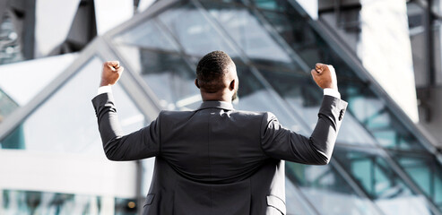 Wall Mural - Business Success Concept. Unrecognizable African Businessman Shaking Fists Shouting In Joy Standing Back To Camera In City. Free Space