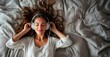 © MYDAYcontent - A young woman lies in bed with her eyes closed, listening to music through headphones. She is relaxed and smiling, with her hair spread out on the bed.