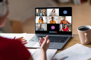 Poster - A woman sits at her desk, participating in a video conference call on her laptop. The screen displays multiple participants, with their names and initials visible