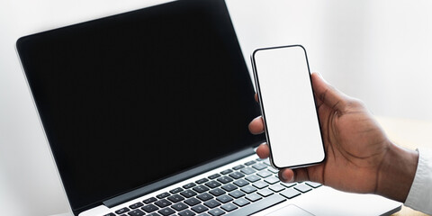 Poster - A hand holds a smartphone with a blank screen near a laptop with a black screen.