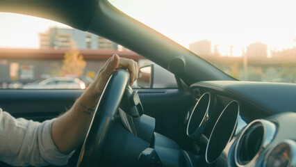 Close up male hands turning steering wheel driving vehicle in sunset sunbeam rays businessman auto owner riding car city road cropped shot driver traveling by modern luxurious automobile own transport