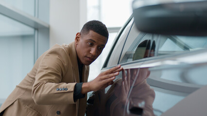 African American man choose car sale new eco electric vehicle at showroom focused male buyer client businessman admiring automobile in dealership touching testing auto quality in salon buy transport