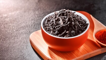 Wall Mural - dry black tea in a bowl on a dark background