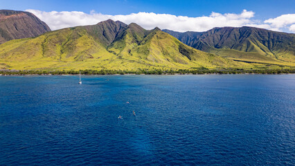 Wall Mural - tourists on kayak tour return to mainland maui. aerial view captures bright blue ocean meeting coast