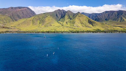 Wall Mural - tourists on kayak adventure return to mainland maui. aerial view captures bright blue ocean meeting 