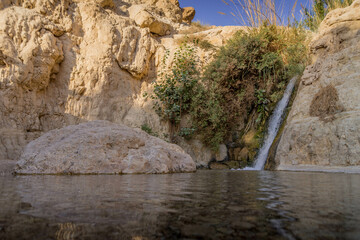 The small waterfall, little pond, and dry rocks deep in the Middle East natural oasis at Ein Gedi national reserve in Israel's desert.
