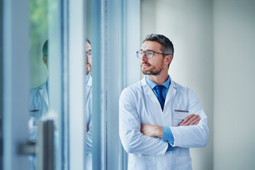 Canvas Print - Mature man, doctor and thinking on healthcare in clinic, physician and arms crossed for diagnosis. Male person, surgeon and planning for treatment or ideas in hospital, window and medical decision