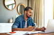 © peopleimages.com - Online, laptop and man in living room with remote work for report, review or update article. Technology, journalist and freelancer for confirm source, proofreading or working on feature story in home