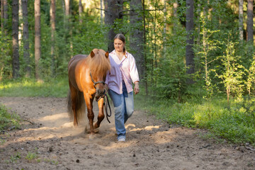 Wall Mural - Woman with Icelandic horse on path middle of the forest