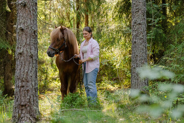 Wall Mural - Woman with Icenlandic horse in forest with sunset on behind