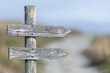 © CHONCHANOK PHOTO - A weathered wooden signpost at a crossroads, with arrows pointing in different directions, symbolizing the choices and paths we take in life