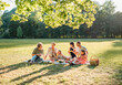 © Soloviova Liudmyla - Big family sitting on the picnic blanket in city park during weekend Sunday sunny day. They are smiling, laughing and eating boiled corn and watermelon. Family values and outdoors activities concept
