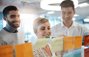 Leinwandbilder - Writing, brainstorming and business people with glass board, project ideas or sticky note in office. Lens flare, diversity and employees in meeting for planning, agenda or teamwork at branding agency