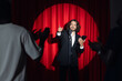© Parilov - Stand up comedian on stage. Young man talks joke into microphone or sings songs