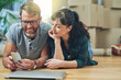 © NonVig/peopleimages.com - Couple, moving and happy browsing on smartphone, smile and ecommerce for apartment purchase with boxes. Living room, people and rent payment on banking fintech app, new home and property investment