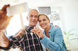 © Penn/peopleimages.com - Moving, selfie and mature couple with key in house for real estate, property ownership or purchase memory. Love, man and woman in digital photography with home relocation, investment or online update